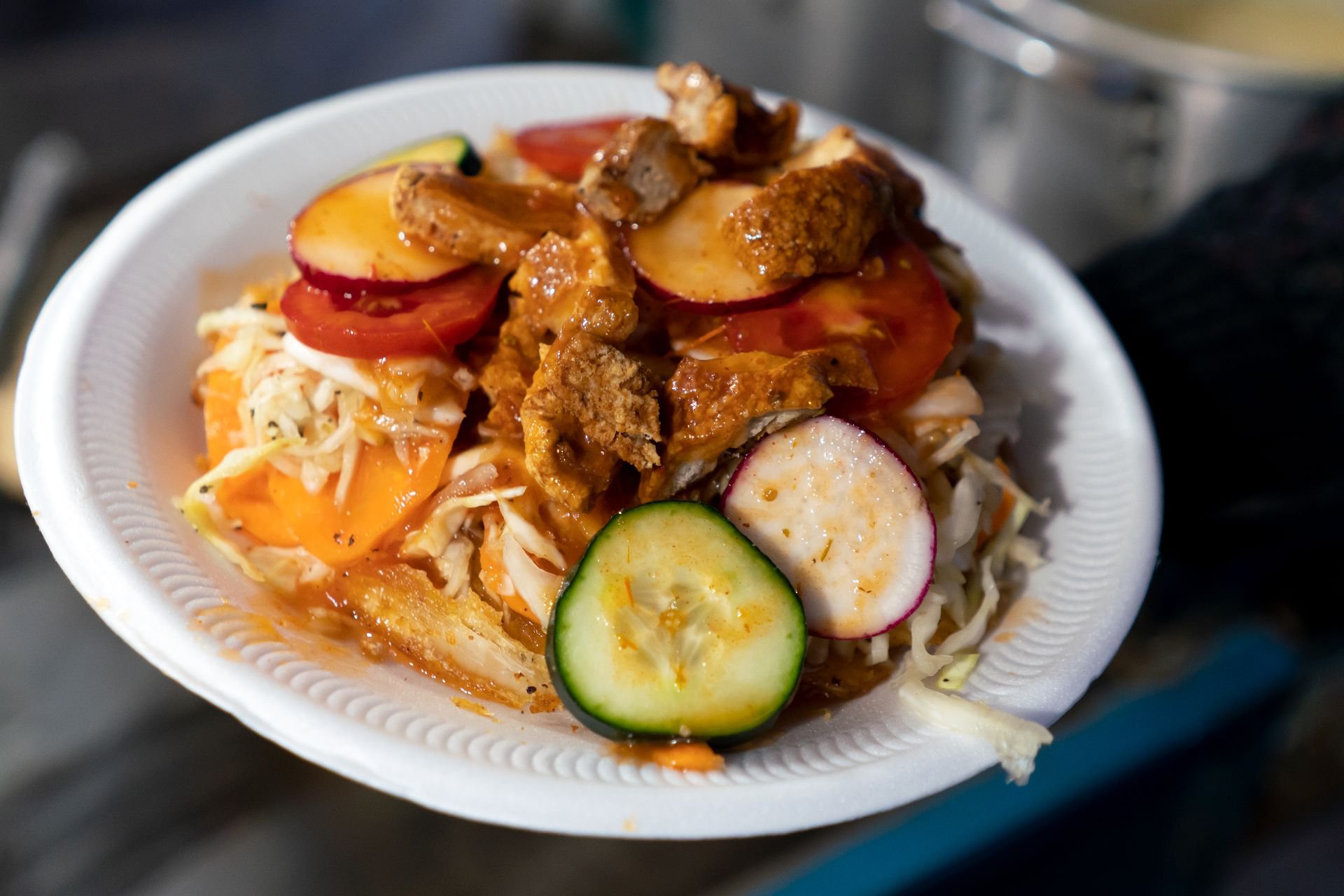 Yuca frita, curtido de repollo, pepino, zanahoria, salsa, chile y trozos de chicharrón